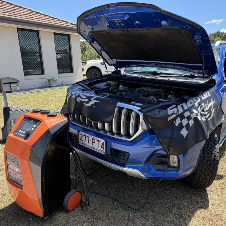 Blue dual-cab ute with the bonnet up, Snap-on fender cover and a Wynn's MultiSERVE machine connected during a mobile service